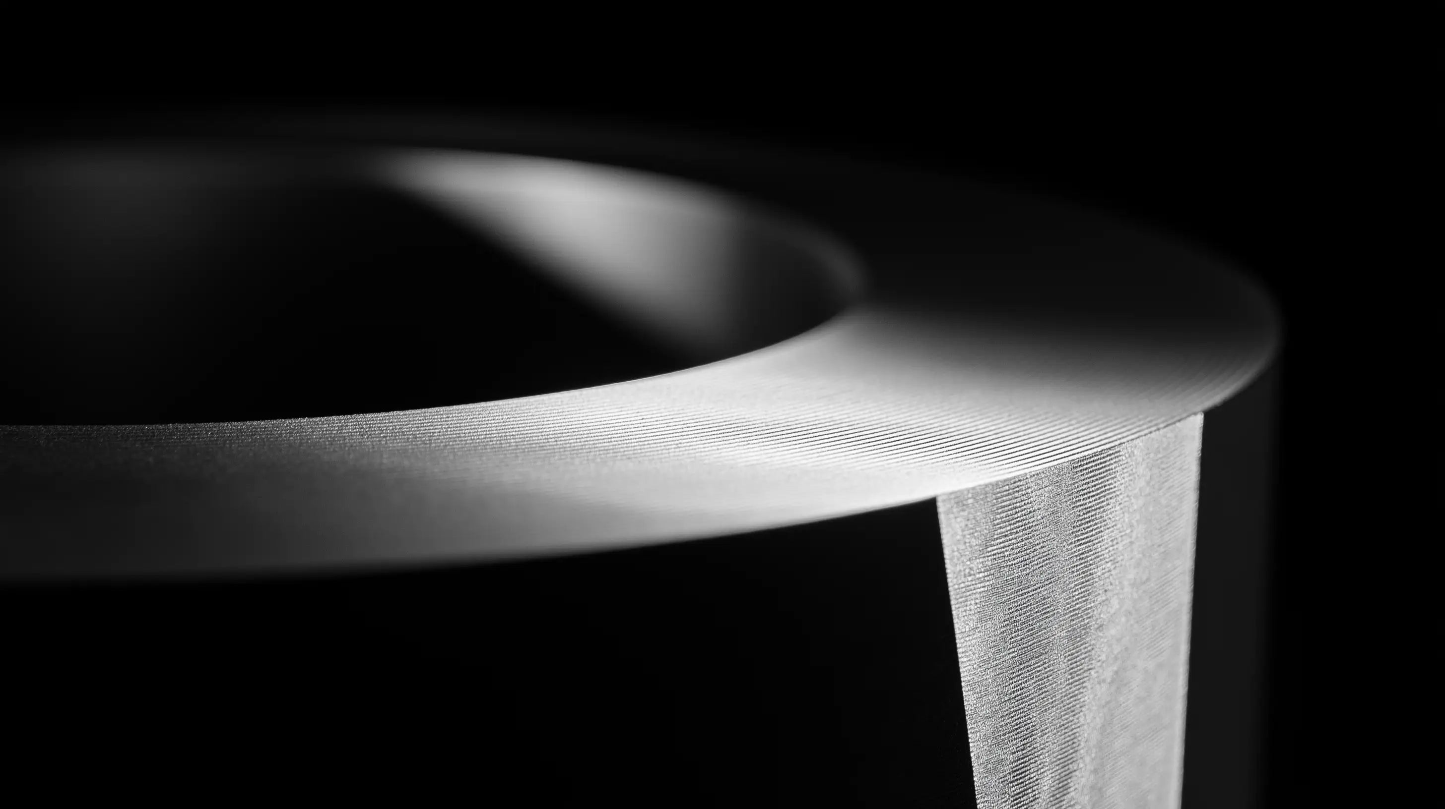 Curved machined surface with fine concentric tool marks lit against black