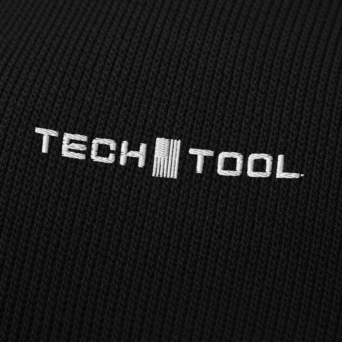 Tech Tool Core Cuffed Beanie, angled macro of white Tech Tool embroidery on fine acrylic knit | Color: Black