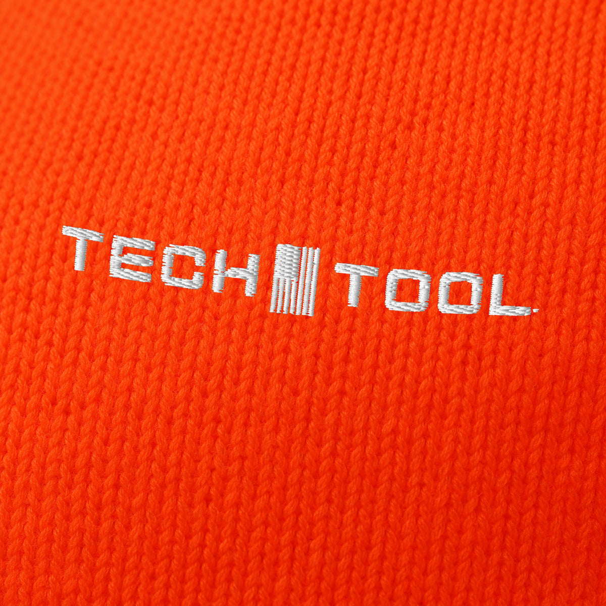 Neon Cuffed Beanie, angled macro of white Tech Tool embroidery on fine acrylic knit | Color: Neon Orange