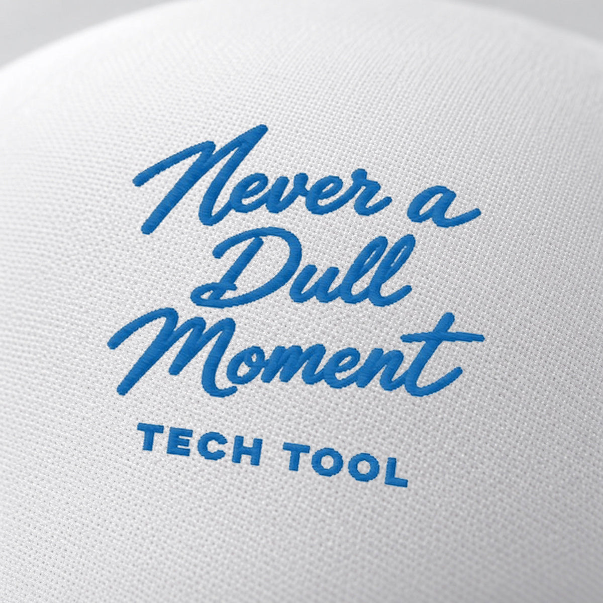 Never a Dull Moment Trucker Hat, oblique macro of Never a Dull Moment script embroidery and Tech Tool signature on white foam | Color: All-American (Red / White / Royal)
