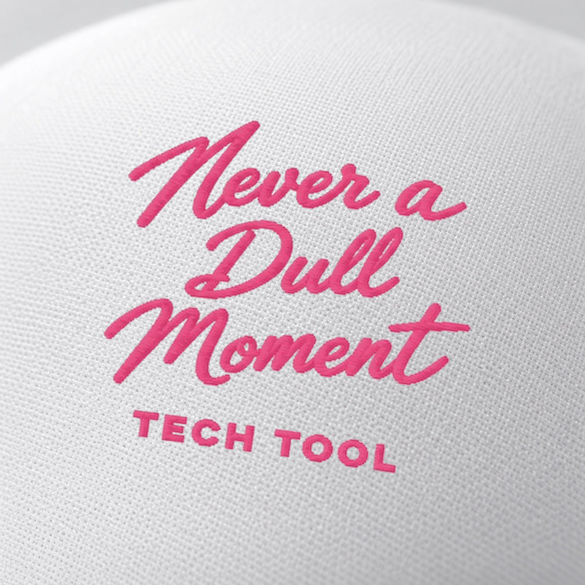 Never a Dull Moment Trucker Hat, oblique macro of Never a Dull Moment script embroidery and Tech Tool signature on white foam | Color: Barbie (Light Pink / White)