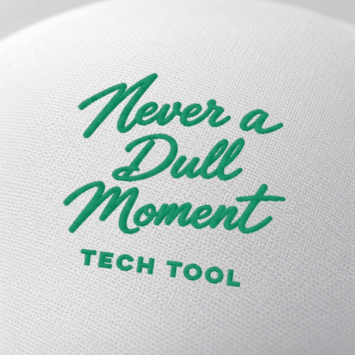 Never a Dull Moment Trucker Hat, oblique macro of Never a Dull Moment script embroidery and Tech Tool signature on white foam | Color: Evergreen (Dark Green / White)