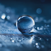 Realistic macro shot of a round water droplet on clean brushed metal illustrating Oemeta Cleaner 100 EC’s deep cleaning performance